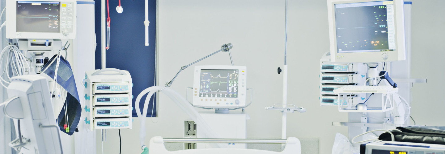 Empty hospital bed in intensive care with monitors all around
