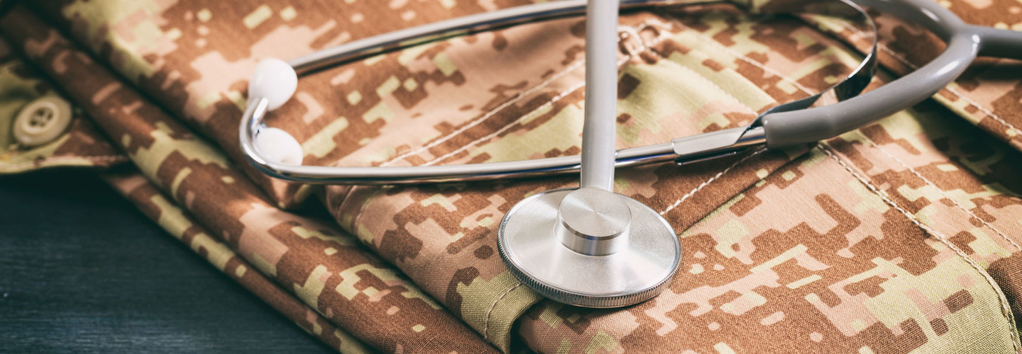 Military medical concept with stethoscope and American military digital pattern uniform, folden on wooden background