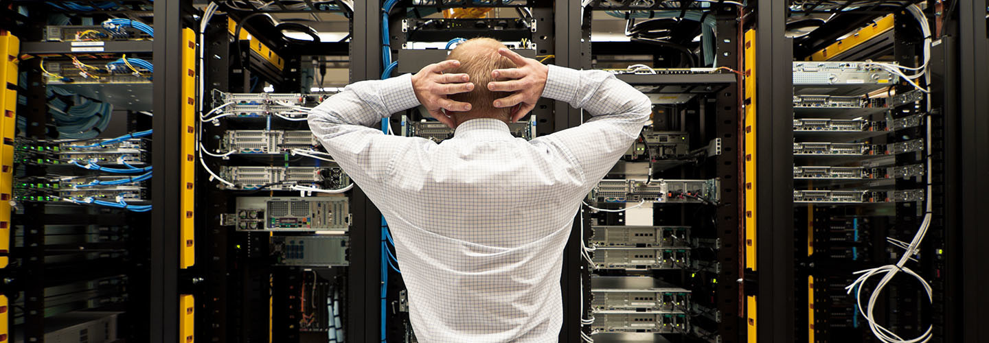 A man looking at a row of servers.