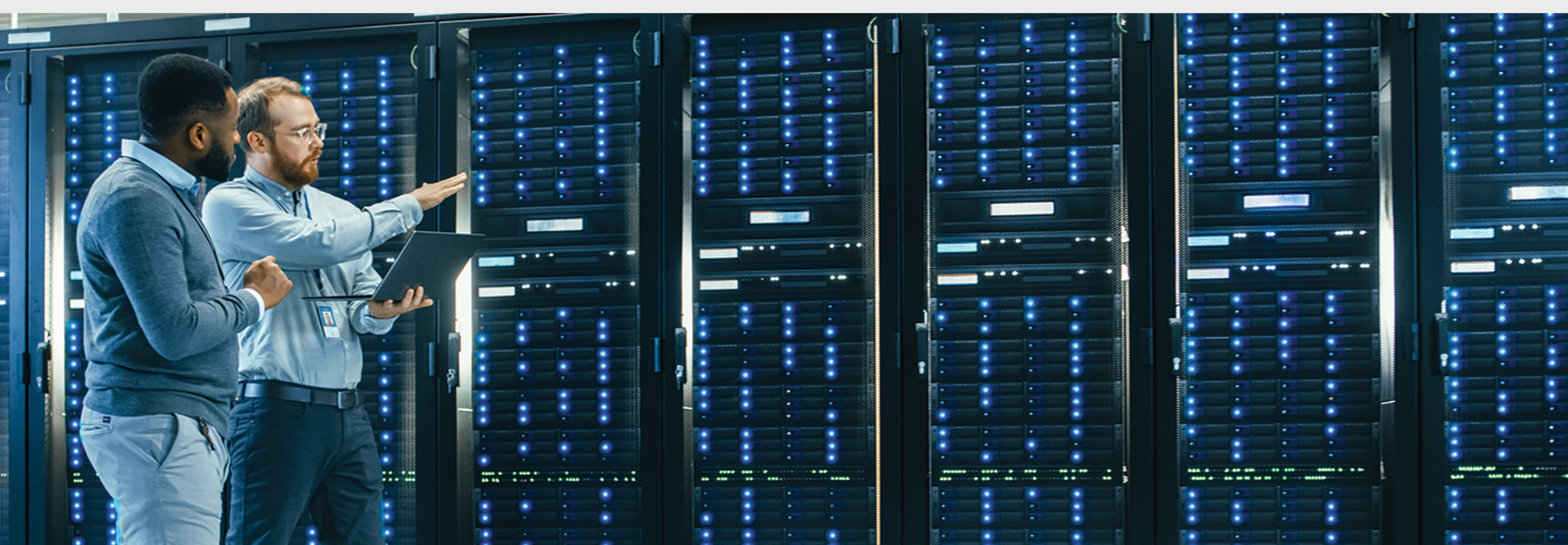 IT technician and engineer colleague talking in a data center next to server racks.