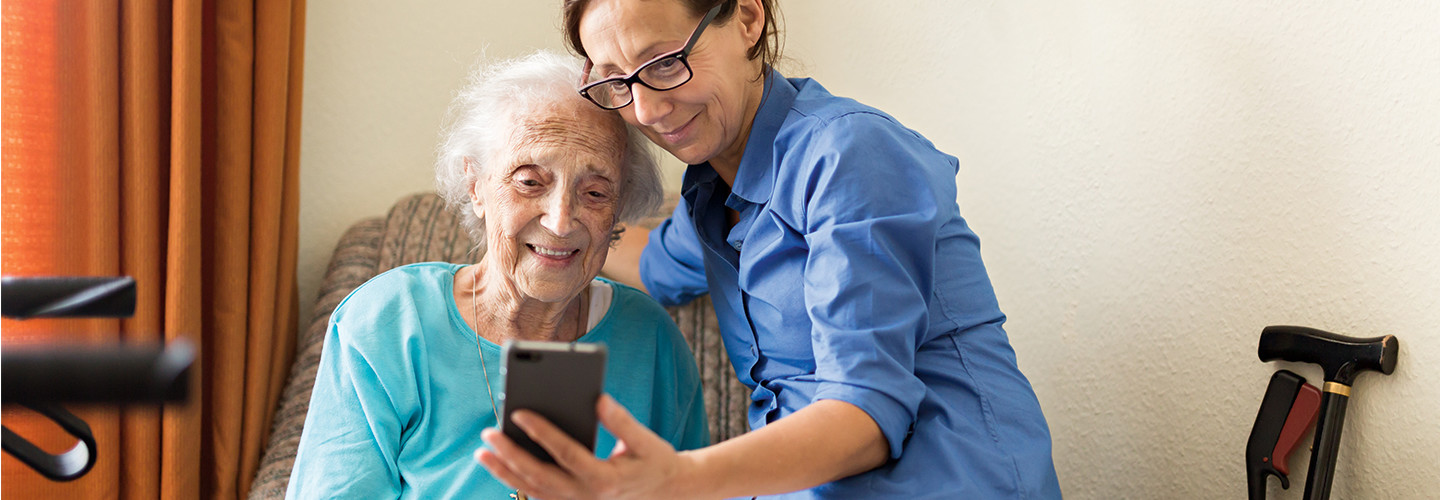 women helps elderly women make video call on phone