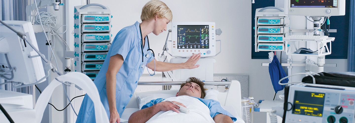 nurse checks on patient in hospital bed surrounded by IoMT devices