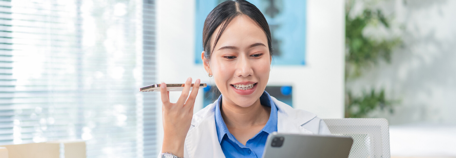 Doctor using phone to dictate to tablet