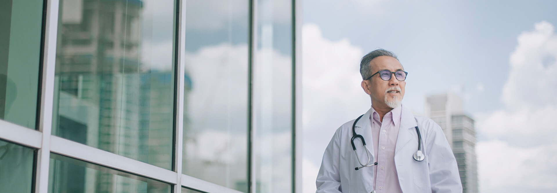 doctor in front of clouds and reflective building
