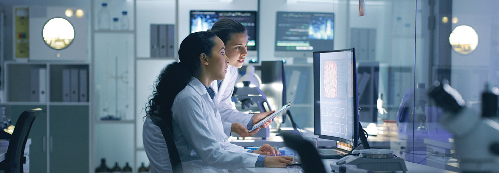 two researchers look at medical data on computer in lab