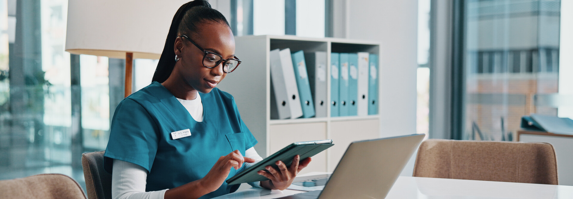 nurse using tablet and laptop at desk