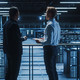 two IT professionals stand over server room