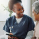 nurse and older adult talk on couch with tablet