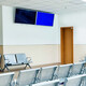 Empty seats in hospital waiting room with a television monitor.