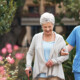 nurse walks with senior woman through a garden