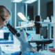 scientist looks through microscope in lab
