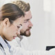 medical researchers look at data on desktop monitor