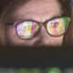 woman wearing glasses looking at healthcare data on screen