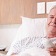 man in hospital bed uses remote to watch tv