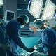 medical team performs surgery in dark room