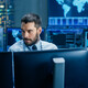 man surrounded by monitors with security data