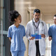 Doctor holding clipboard walks with medical students