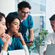 medical and IT team collaborate at table in front of laptop