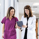 two clinicians walking down hallway looking at a tablet