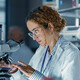 healthcare researcher looks through microscope in dark lab