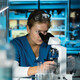 scientist looks through microscope in lab