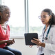 doctor talks to patient in exam room while holding a tablet
