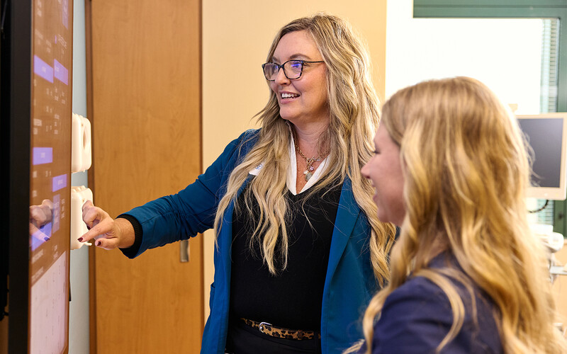 two women look at digital whiteboard