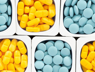 Top view of lots of pills held in plastic containers in a crisscross pattern