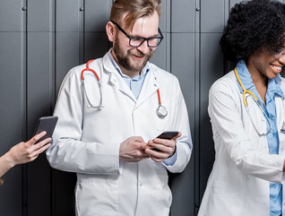 Multi ethnic group of medics standing with phones on the gray wall background