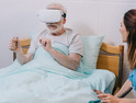 Nurse sitting by patient using VR headset