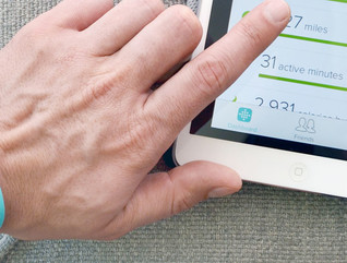 Close up of a man wearing a Fitbit Flex using the App on an iPad Mini