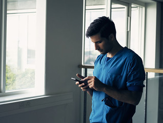 Shot of a focused young male doctor standing while being on his cellphone inside of a hospital