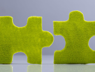 Side View Of Two Miniature Human Figures Solving Green Jigsaw Puzzles On Grey Background