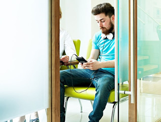 Young man sitting in waiting room at dental clinic using mobile phone