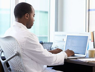 Doctor Wearing White Coat Working On Laptop In Office