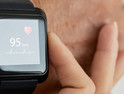 Close-up shot of unrecognizable doctor checking pulse of her senior patient with help of smart watch, blurred background