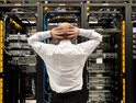 A man looking at a row of servers.