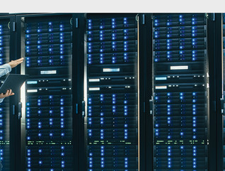 IT technician and engineer colleague talking in a data center next to server racks.