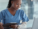 female nurse holding clipboard looking at laptop