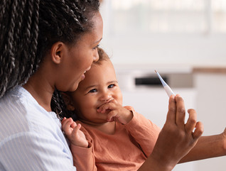 mother takes baby's temperature on telehealth call with doctor