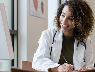 Doctor writing information from computer