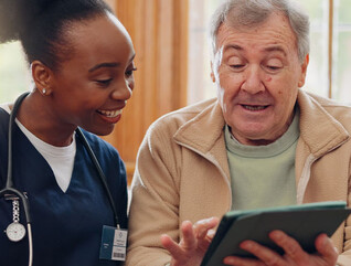 nurse and senior laugh while looking at tablet