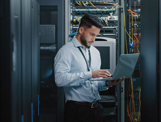 man on laptop in server room