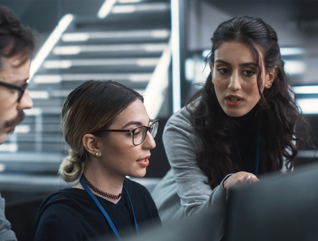 cybersecurity team members talk in front of monitors