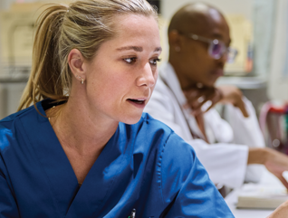 nurses talk in front of desktop computer