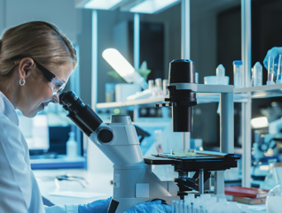 scientist looks through microscope in lab