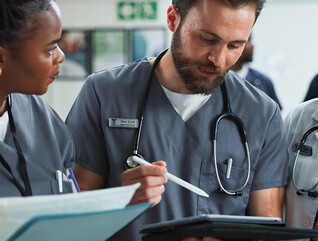Team of clinicians talk over tablet
