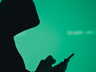 silhouette of hooded figure on phone