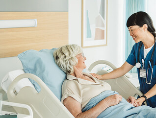 nurse cares for senior in hospital bed