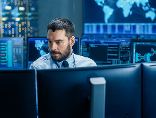 man surrounded by monitors with security data